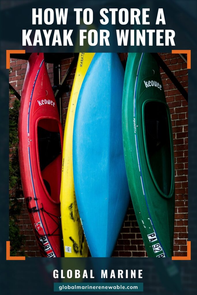How to Store a Kayak for Winter: Four plastic kayaks, red, yellow, blue and green, stored standing on end against a brick wall